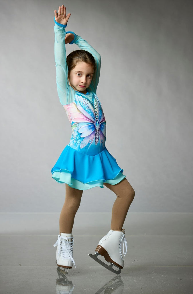 Young girl wearing a teal and blue long-sleeve figure skating dress featuring a butterfly design, purple-pink details, and crystal embellishments, model Butterfly, front view – EliteXpression
Jeune fille qui porte une robe de patinage artistique bleue et turquoise avec des manches longues, un design de papillon, des détails rose-mauve, et ornée de cristaux, modèle Butterfly (Papillon), vue de face – Elite Xpression
D440-BUTBLU