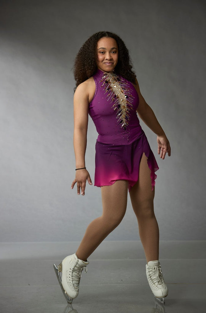One-of-a-kind purple figure skating competition dress with asymmetrical chiffon skirt, high-neck sleeveless bodice, and crystal embellishments, model Miranda, pose front view – Elite Xpression
Robe unique de compétition de patinage artistique avec jupe en chiffon asymétrique, corsage sans manches à col montant et ornements en cristaux, modèle Miranda, pose vue de face – Elite Xpression.

